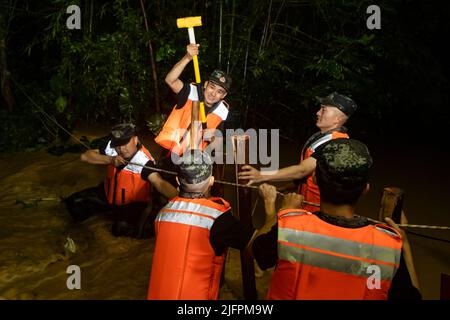 BEIHAI, CHINE - le 4 JUILLET 2022 - des policiers et des soldats armés utilisent des sacs de sable, des piquets et des planches de bois pour construire un barrage pour bloquer la brèche à Beihai Banque D'Images