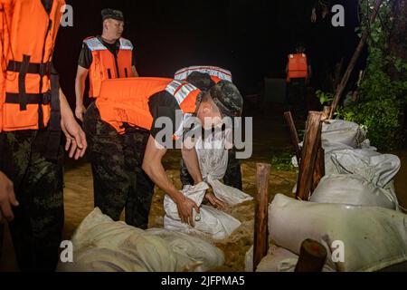 BEIHAI, CHINE - le 4 JUILLET 2022 - des policiers et des soldats armés utilisent des sacs de sable, des piquets et des planches de bois pour construire un barrage pour bloquer la brèche à Beihai Banque D'Images