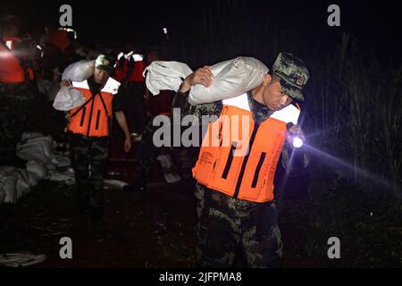 BEIHAI, CHINE - le 4 JUILLET 2022 - des policiers et des soldats armés utilisent des sacs de sable, des piquets et des planches de bois pour construire un barrage pour bloquer la brèche à Beihai Banque D'Images