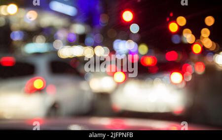 Image floue des voitures intérieures avec des lumières de bokeh provenant des embouteillages la nuit. Vue de l'intérieur d'une voiture Banque D'Images