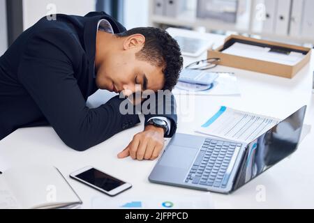 Un lit quand vous en avez besoin. Photo d'un jeune homme d'affaires qui dormait à son bureau. Banque D'Images