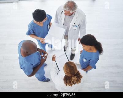 Trouver des solutions à des cas complexes sous plusieurs perspectives. Prise de vue en grand angle d'un groupe de médecins ayant une discussion ensemble dans un Banque D'Images