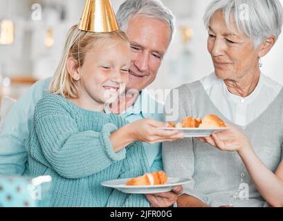 Chaque bodys se fait un gâteau. Photo courte d'une adorable petite fille célébrant un anniversaire à la maison avec ses grands-parents. Banque D'Images