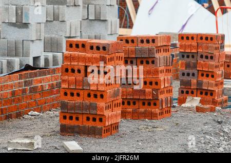 Briques rouges et blocs de béton livrés sur le chantier et placés à côté du lieu de travail prêt pour les briques Banque D'Images