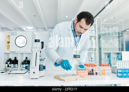 Je dois perfectionner ce traitement. Photo d'un jeune scientifique travaillant avec des échantillons dans un laboratoire. Banque D'Images