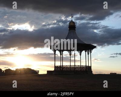 Les rayons du soleil se brisent à travers les nuages, avec le Wallace Bandstand, construit en 1884 sur Nairn Links, silhoueté contre le ciel du soir d'été. Banque D'Images