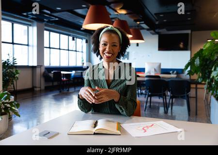 Portrait d'une jeune femme d'affaires afro-américaine souriante avec journal intime à la réception au bureau Banque D'Images