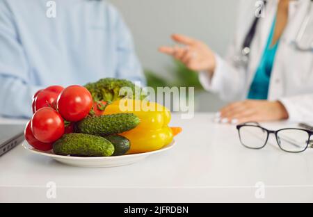 Légumes sur la table de diététicien ou de nutritionniste donnant la consultation au patient en arrière-plan Banque D'Images