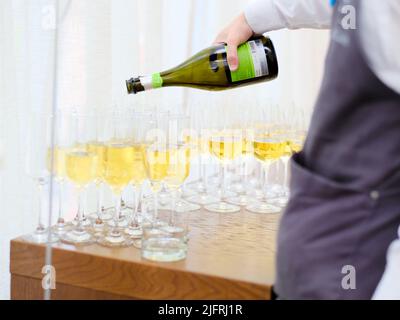 Moscou. Russie. 18 juin 2022. La main du serveur verse du champagne dans des gobelets en verre. Mise au point sélective. Le serveur du banquet verse du vin en verres. Banque D'Images