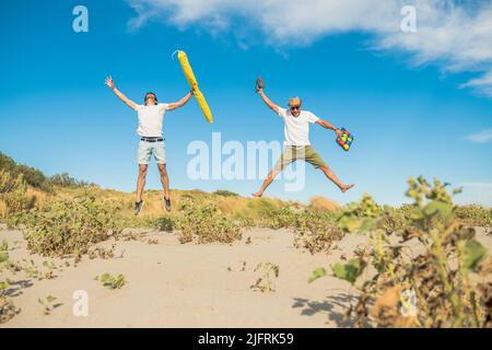 Des amis heureux appréciant des vacances d'été sur la plage au coucher du soleil - deux garçons sautant sur la plage au lever du soleil - concept vacances Banque D'Images