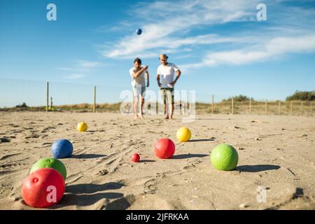 Les touristes jouent à un jeu actif, pétanque sur une plage de sable au bord de la mer - Groupe de jeunes jouant à la boule en plein air en vacances à la plage Banque D'Images