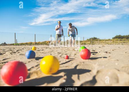 Les touristes jouent à un jeu actif, pétanque sur une plage de sable au bord de la mer - Groupe de jeunes jouant à la boule en plein air en vacances à la plage Banque D'Images