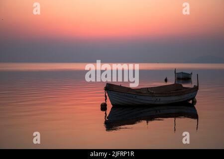 Photographie horizontale d'un lever de soleil dans la Mar Menor de Murcia, Espagne, avec des bateaux de pêche en premier plan et un ciel rose qui se reflète dans le cal Banque D'Images