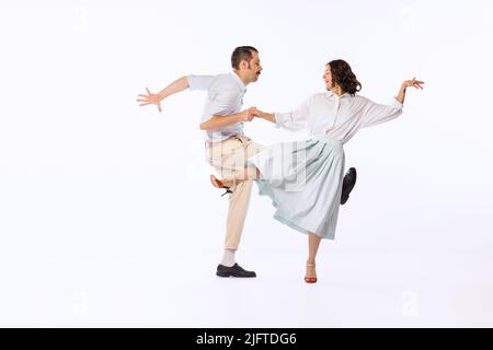 Portrait de jeune couple gai, homme et femme, dansant boogie woogie isolé sur fond blanc studio Banque D'Images