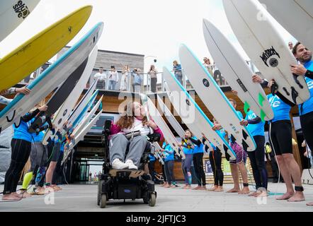 Détenteur de bâton et fondateur du club de boccia en fauteuil roulant de Bristol, Georgina Moore est accueillie par une garde d'honneur de surf alors qu'elle porte le bâton de la Reine à la vague de Bristol. Le relais Queen's Baton est arrivé à Bristol , pendant la dernière étape de son voyage de 2 500 miles aux Jeux du Commonwealth de Birmingham 2022. Date de la photo: Mardi 5 juillet 2022. Banque D'Images