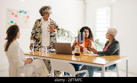 Diverses femmes d'affaires ayant une discussion pendant une réunion. Groupe d'entrepreneurs féminins partageant des idées créatives dans une salle de réunion. Entreprises multiculturelles