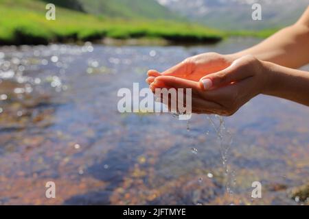 Clos eup portrait d'une femme en forme de cuvette qui attrape l'eau dans une rivière dans une haute montagne Banque D'Images