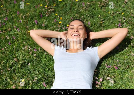 Vue de dessus d'une femme se reposant sur l'herbe et riant dans la montagne ou le parc Banque D'Images