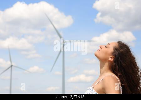 Profil d'une femme détendue respirant de l'air frais dans une ferme éolienne Banque D'Images