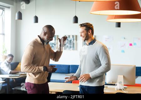 Les hommes d'affaires multiraciaux gaies se sont mis à la mode tout en restant dans un bureau créatif Banque D'Images