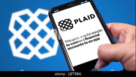 San Francisco, Etats-Unis, juin 2022: Main tenant un téléphone avec la page d'accueil de Plaid à l'écran. Logo écossais flou sur fond bleu. Plaid est un service financier Banque D'Images