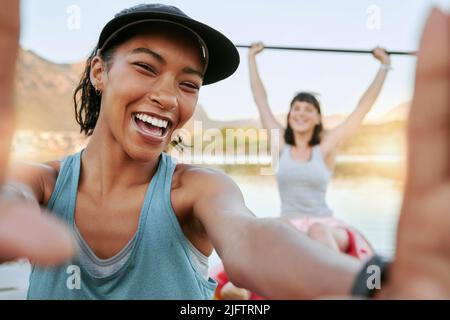 Deux amis souriants prenant des selfies et faisant du kayak ensemble sur un lac en été. Souriante et heureuse, les femmes joueuses se colent dehors dans la nature avec de l'eau Banque D'Images