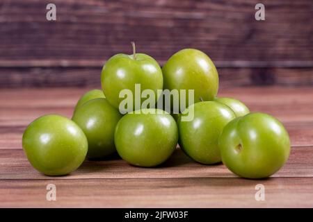 Prune verte sur fond de bois. Tas de prunes vertes. Gros plan Banque D'Images