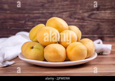 Abricots sur fond de bois. Pile d'abricots frais dans une assiette blanche. Gros plan Banque D'Images