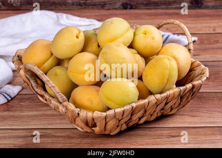 Abricots sur fond de bois. Un tas d'abricots frais dans un panier. Gros plan Banque D'Images