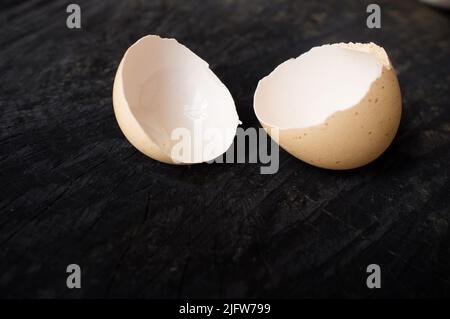 La coquille d'œuf repose sur une table de cuisine sombre Banque D'Images