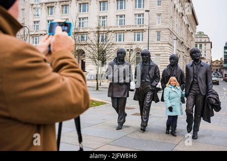 Touristes se photographiant à côté de la statue des Beatles dans leur ville natale de Liverpool, à Pier Head sur le front de mer de Liverpool. Leverpool, Merseys Banque D'Images