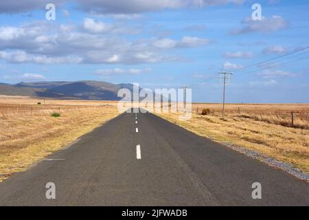 Paysage de route goudronnée menant à la ferme fraîchement récoltée du Cap-Occidental, Afrique du Sud. Ciel bleu, campagne pittoresque rue de labouré Banque D'Images