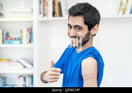 Homme arabe montrant le pouce vers le haut après la troisième vaccination contre Covid 19 comme protection contre le coronavirus Banque D'Images