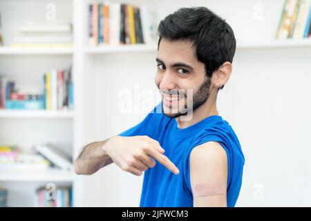 Rire arabe homme montrant du plâtre sur le bras après la troisième vaccination contre Covid 19 comme protection contre le coronavirus Banque D'Images