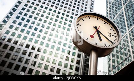 Horloges des Docklands, Londres, Royaume-Uni. Une vue basse et grand angle de la tour Canary Wharf en face de l'une des six horloges publiques de Konstantin Grcic. Banque D'Images