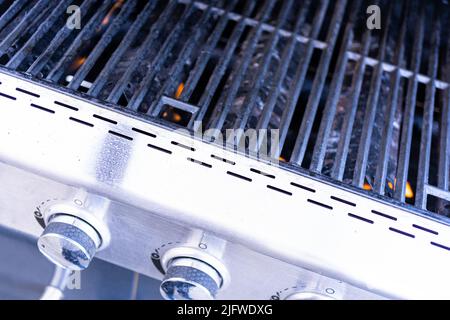 Vue rapprochée des grilles en fonte d'un gril à gaz extérieur. Banque D'Images