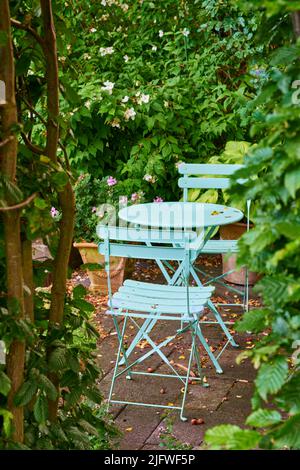 Deux chaises en métal vert et une table dans une cour privée paisible et paisible dans une arrière-cour intérieure, le jour d'été. Petit mobilier de jardin extérieur Banque D'Images