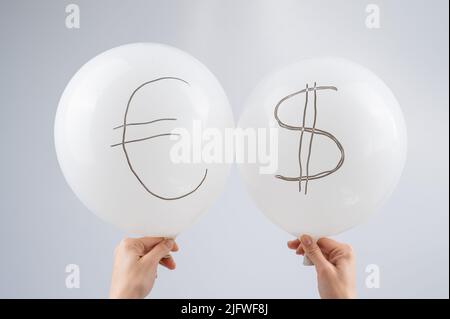 Femme tenant deux ballons blancs avec des symboles dollar et euro. Banque D'Images