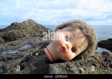 Une ancienne tête de poupée abandonnée sur les rochers Banque D'Images