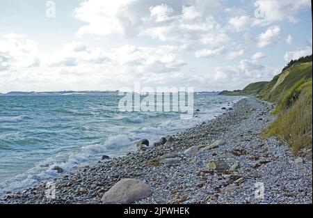 Côte du Kattegat - Helgenaes, Danemark. Vagues de l'océan se lavant sur des pierres de plage vides. Calme et paisible paradis du paysage marin et du ciel pour l'été Banque D'Images