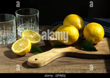 Citrons sur un bureau en bois et sur une table en bois avec deux verres pour la future limonade Banque D'Images