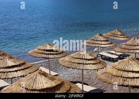 Plage de galets vide avec parasols en osier et chaises longues. Vue pittoresque sur la mer bleue, station balnéaire luxueuse Banque D'Images