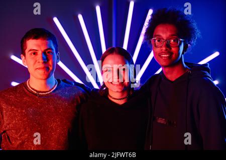 portrait d'arbre divers jeunes souriant à l'appareil photo dans un décor futuriste au néon Banque D'Images