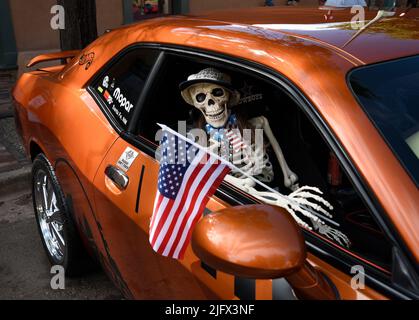 Un squelette en plastique de nouveauté porte un drapeau américain dans un Dodge Challenger 2011 exposé lors d'un salon automobile du 4 juillet à Santa Fe, Nouveau-Mexique. Banque D'Images