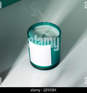 Bougie de cire de soja aromatique dans un verre d'aigue-marine avec des ombres. Une image créative d'une bougie aromatique avec une fumée de la mèche.le concept de coziness Banque D'Images