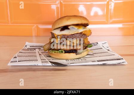 Hamburger à plusieurs niveaux avec deux steaks, œuf frit, rondelles d'oignon, sauce, fromage fondu, tranches de tomate et de laitue Banque D'Images