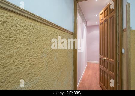 Hall d'entrée d'une maison aux murs peints en rose lisse, mur extérieur rugueux jaune et porte en bois lambrissée vintage Banque D'Images