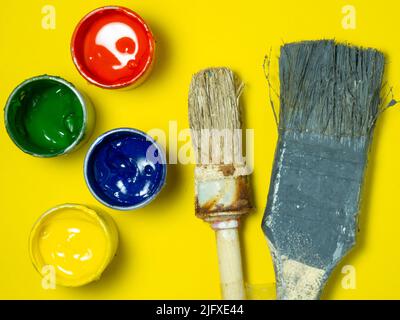 Pots de peinture et brosses anciennes sur fond jaune. Banques de gouache. Arrière-plan lumineux. Créatif . Atelier de l'artiste. Banque D'Images