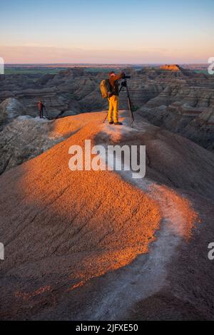 Interior, SD, Etats-Unis - 21 juin 2022 : deux photographes photographient la vallée de la rivière Blanche et surplombent le parc national des Badlands au lever du soleil. Banque D'Images