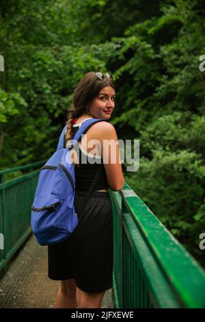 Randonneur regardant la caméra en traversant un pont en montagne Banque D'Images